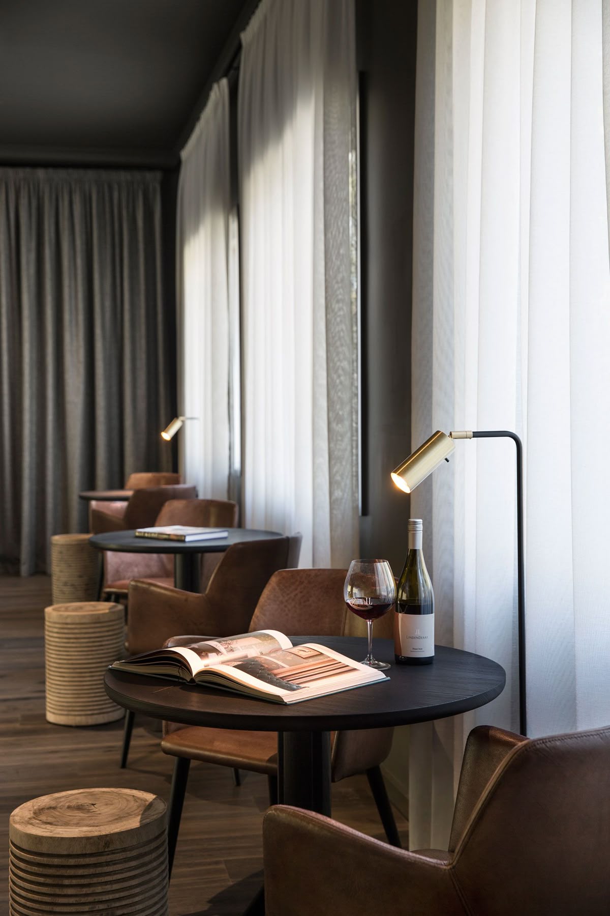 Intimate lounge with leather reading chairs, brass task lamp and wine — warmth and considered hospitality atmosphere